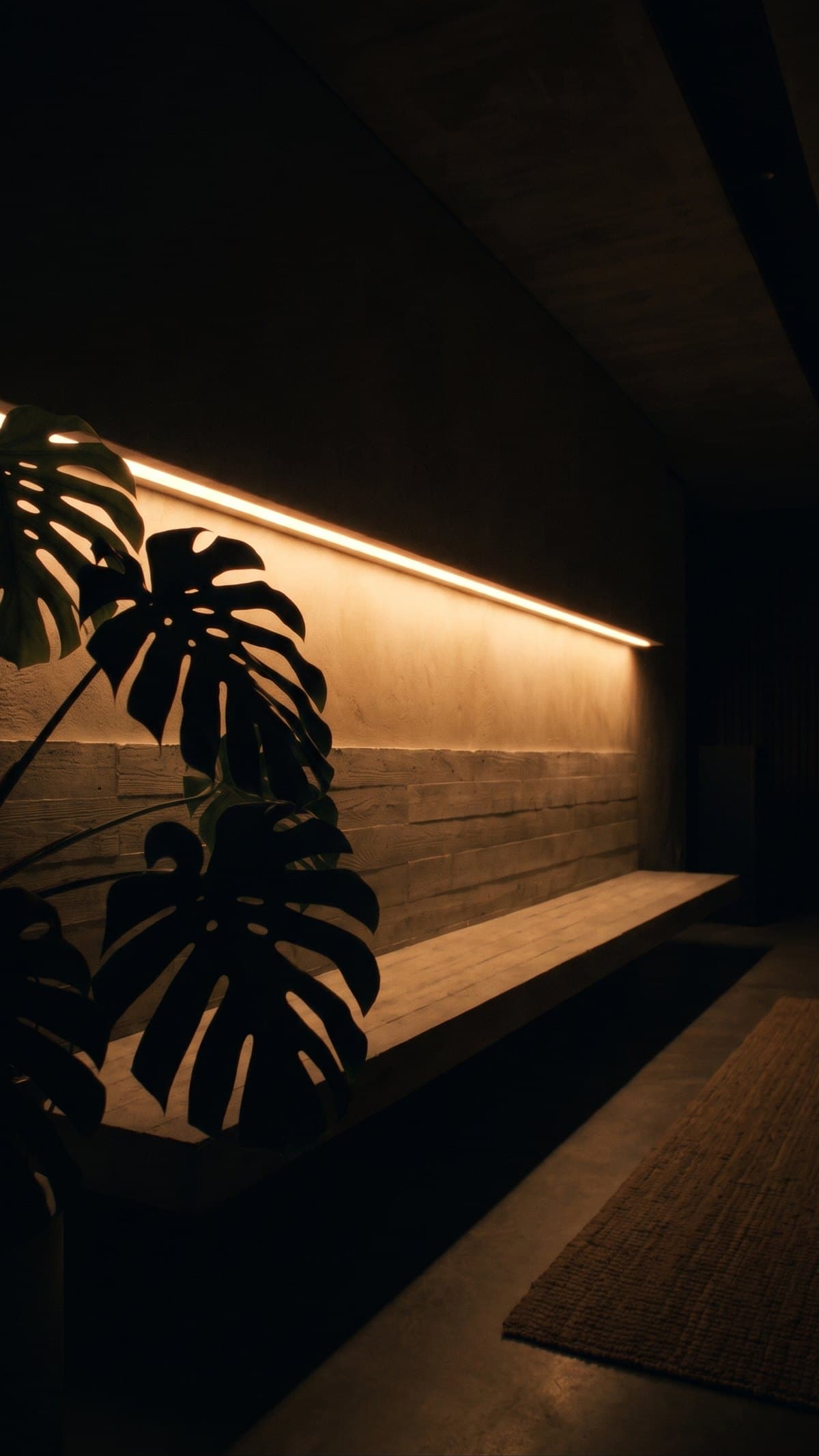 A dark living room with a warm line of light recessed along one wall